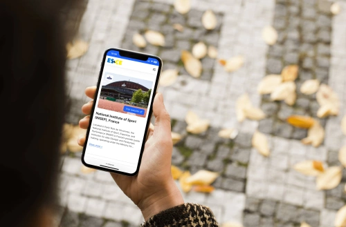 Bild på en mobil i handen på en person utomhur som besöker esnce.eu (en sajt som Balowie byggt och designat)